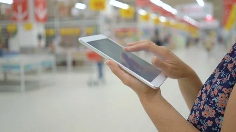 Woman hands touching tablet screen in supermarket: Stock Footage 76860549