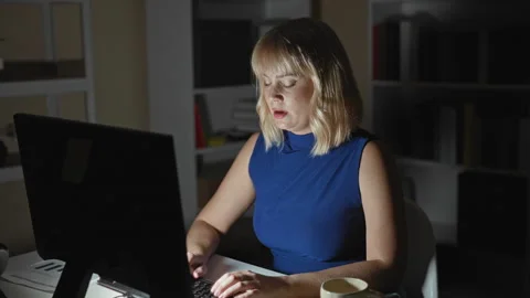 Woman with hands typing on keyboard at computer in an office building at ni.. Stock Footage 337387836