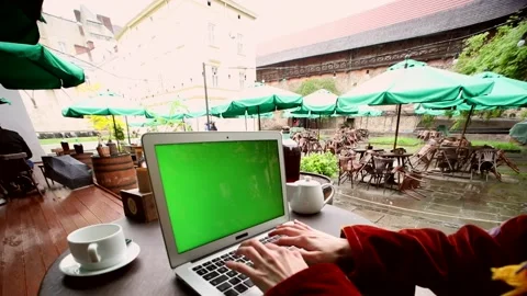 Woman hands using laptop with empty green screen sitting in modern cafe outside. Vidéo 131803436