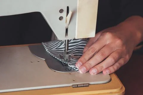 Woman hands using the sewing machine to sew the face medical mask during the Stock Photos