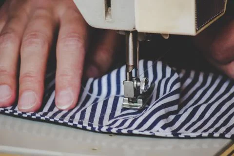Woman hands using the sewing machine to sew a colorful face medical mask during Stock Photos