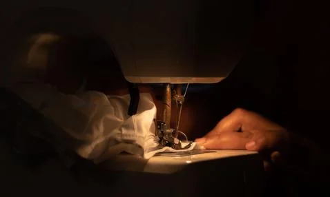 Woman hands using the sewing machine to sew a pant. Stock Photos