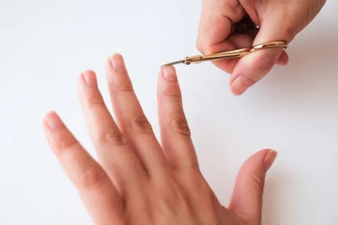 Woman hands using a small scissors to cut her fingernails on a white backgrou Stock Photos
