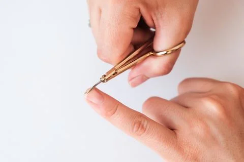 Woman hands using a small scissors to cut her fingernails on a white backgrou Foto stock