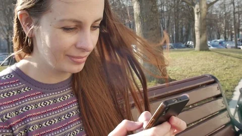 Woman hands using smartphone outside, sitting on bench in park Stock Footage 77676872