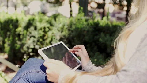 Woman hands using tablet computer sitting in the park Stock Footage 79007322