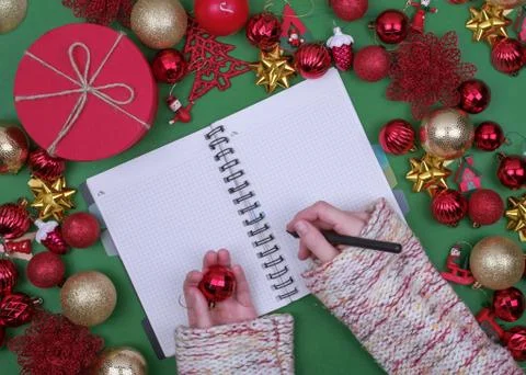 Woman hands write Christmas checklist, letter to Santa on green background wi Stock Photos