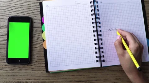 Woman hands writing note over office desk with notebook and smart phone with a Stock Footage