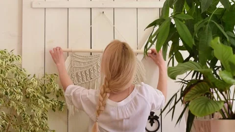 Woman hangs macrame-style decor on the wall in a home workshop. Stock Footage 154342781