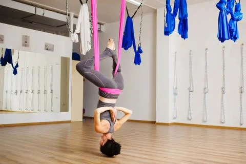 Woman hangs upside down doing aero anti gravity yoga exercises Stock-Fotos