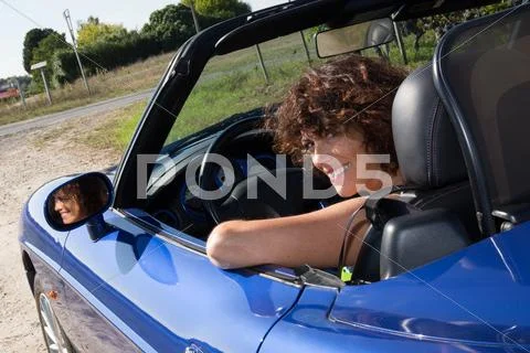 Woman happy in blue cabriolet driving on road trip Stock Photos
