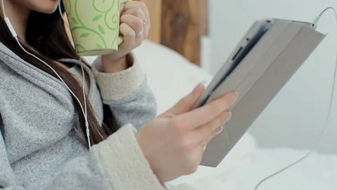 Woman happy using digital tablet shopping online and drinking coffee in bed Stock Footage 73752470