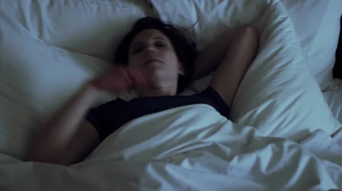 Woman has insomnia, tosses and turns in bed - wide shot Stock Footage