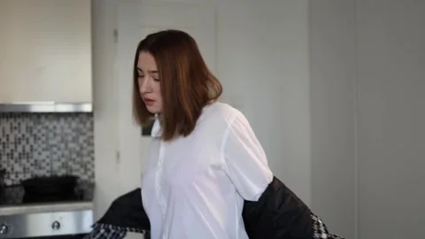 Woman hastily putting on jacket while rushing to leave home Stock Footage 327217033