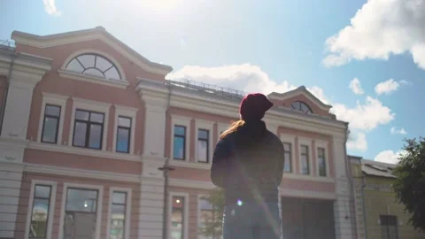 Woman in hat and jacket looks at building, draws picture, makes sketch, sunny Stock Footage 140962012
