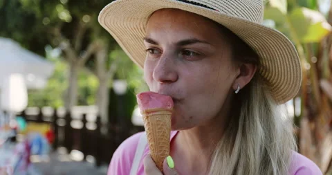 Woman in a hat eats pink ice cream in a cone on vacation. Stock Footage 140158669