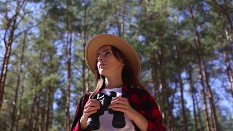 Woman in a hat holds binoculars while hiking in forest. Concept hike, tourism. Stock-Footage 149944533