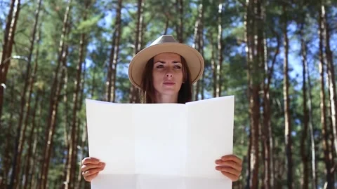 Woman in a hat looks at a map in the forest. Concept hike, tourism. Video stock 149944553