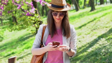 Woman in hat outdoor in spring using phone Stock Footage 148432910