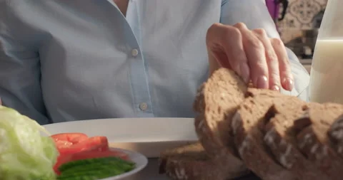 A woman having breakfast putting a slice of artisan rye bread on a plate Stock Footage 232955689