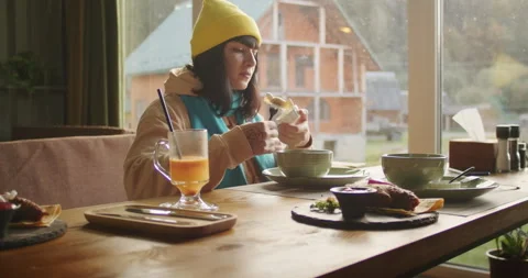 Woman having breakfast in a rustic cabin, enjoying a creamy soup. Cozy mountain Stock Footage 264201423