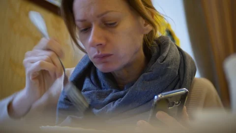 A woman is having dinner in a cafe using a smartphone. 4k Stock Footage 86254917