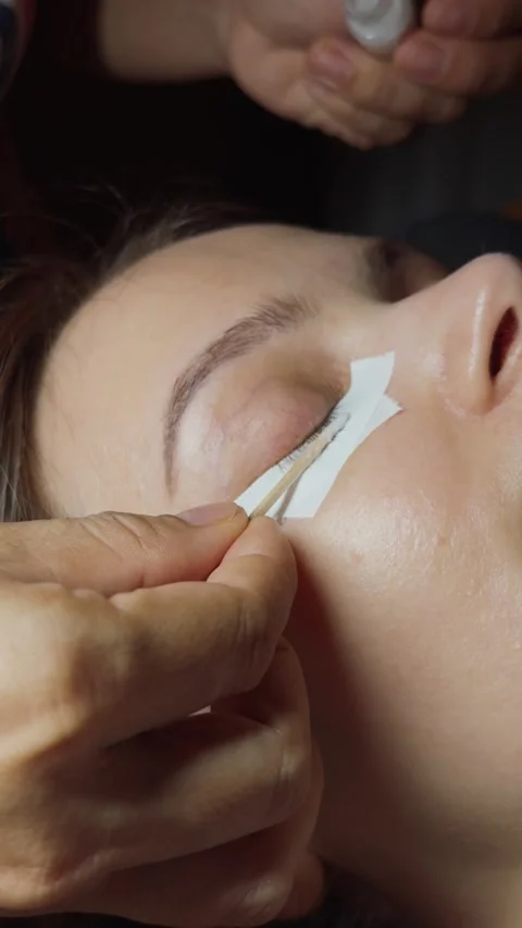 Woman having eyelash extensions applied during a beauty treatment, enhancing Stock Footage 332834032