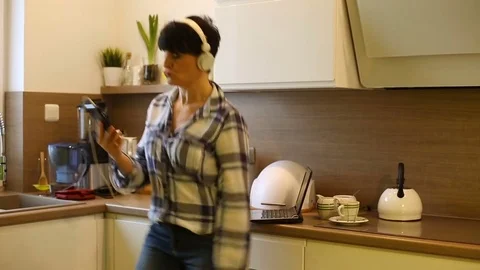 Woman having fun in the kitchen while listening music and dancing Stock Footage 73309263