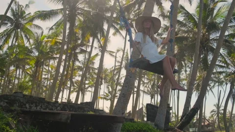 Woman is having fun on swing between palms Stock Footage 134612692