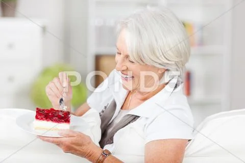 Woman having pastry while sitting on sofa Stock Photos