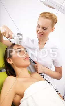 Woman having a stimulating facial treatment from a therapist Stock Photos