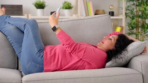 Woman having video call while relaxing on sofa Stock Footage 249728675