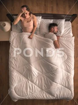 The woman with headache sit on the bed near the man. view from above Stock Photos