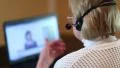 Woman with headphones on computer talks to a customer HD Footage