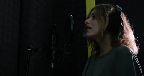 Woman in headphones singing in microphone Stockbeeldmateriaal 149083553