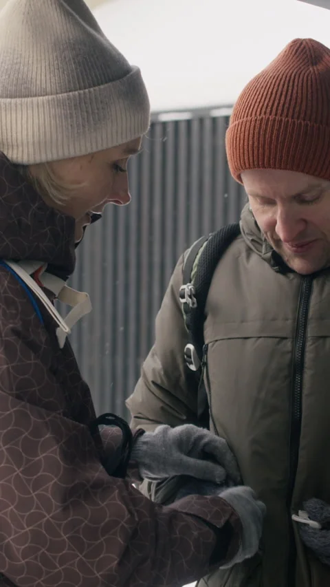 Woman Helping Man with Backpack Straps for Outdoor Winter Activity Stock Footage 341301299
