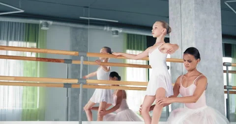 Woman helps dancer do exercises for legs in ballet studio 库存影片 141409587