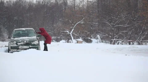 Woman helps to release car from snow trap on country road Stock Footage 22733054