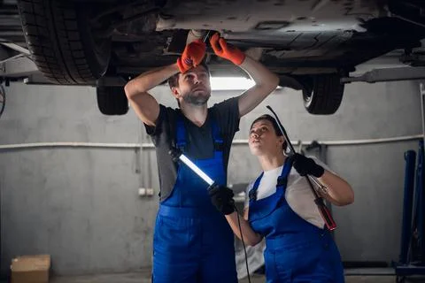 Woman helps a techie with torch checking car Stock Photos