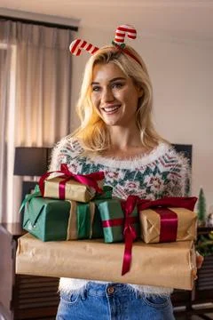 Woman in her 20s holding wrapped gifts at home, wearing fuzzy sweater and candy Foto stock