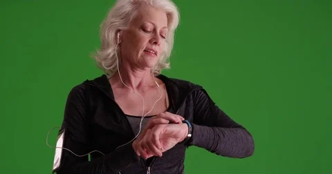 Woman in her 50s using smart watch checking her pulse after jog on greenscreen Stock Footage