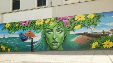 A woman with her dog passes a mural Hastings is Green 6K Stock Footage 329960153