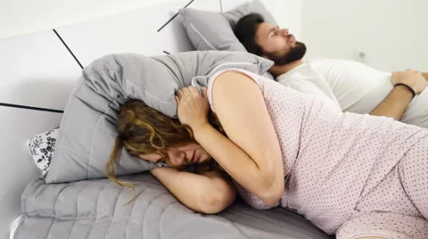 Woman hiding her head under the pillow while sleeping with a man slow motion Stock Footage 59189542