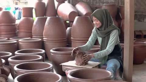 Woman in hijab sitting processing clay into pottery in studio Stock Footage 170352637