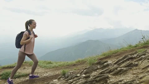 Woman hiker with backpack during the ascent of the peak in the summer Stock Footage 280176653