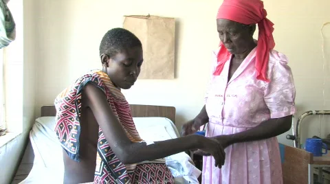 Woman with HIV/AIDS receives treatment from mother, in a AIDS ward in Africa Stock Footage