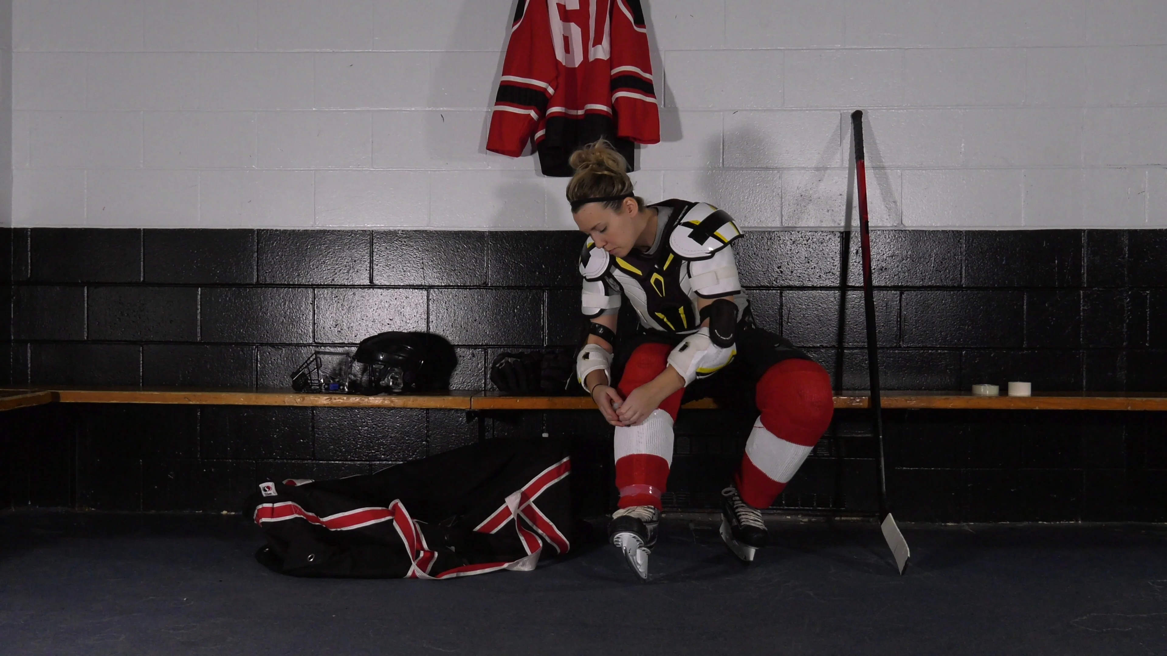 woman hockey player getting undressed removing tape wide front view