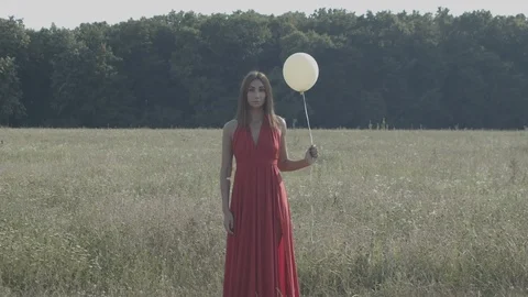 Woman holding and releasing balloon on field and forest Stock Footage