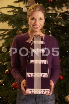 Woman Holding Christmas Gifts In Front Of Tree Stock Photos