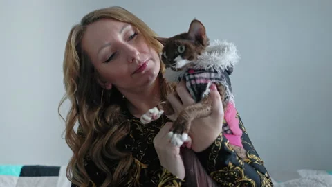 A woman holding Devon Rex cat wearing a jacket Stock Footage 233673241